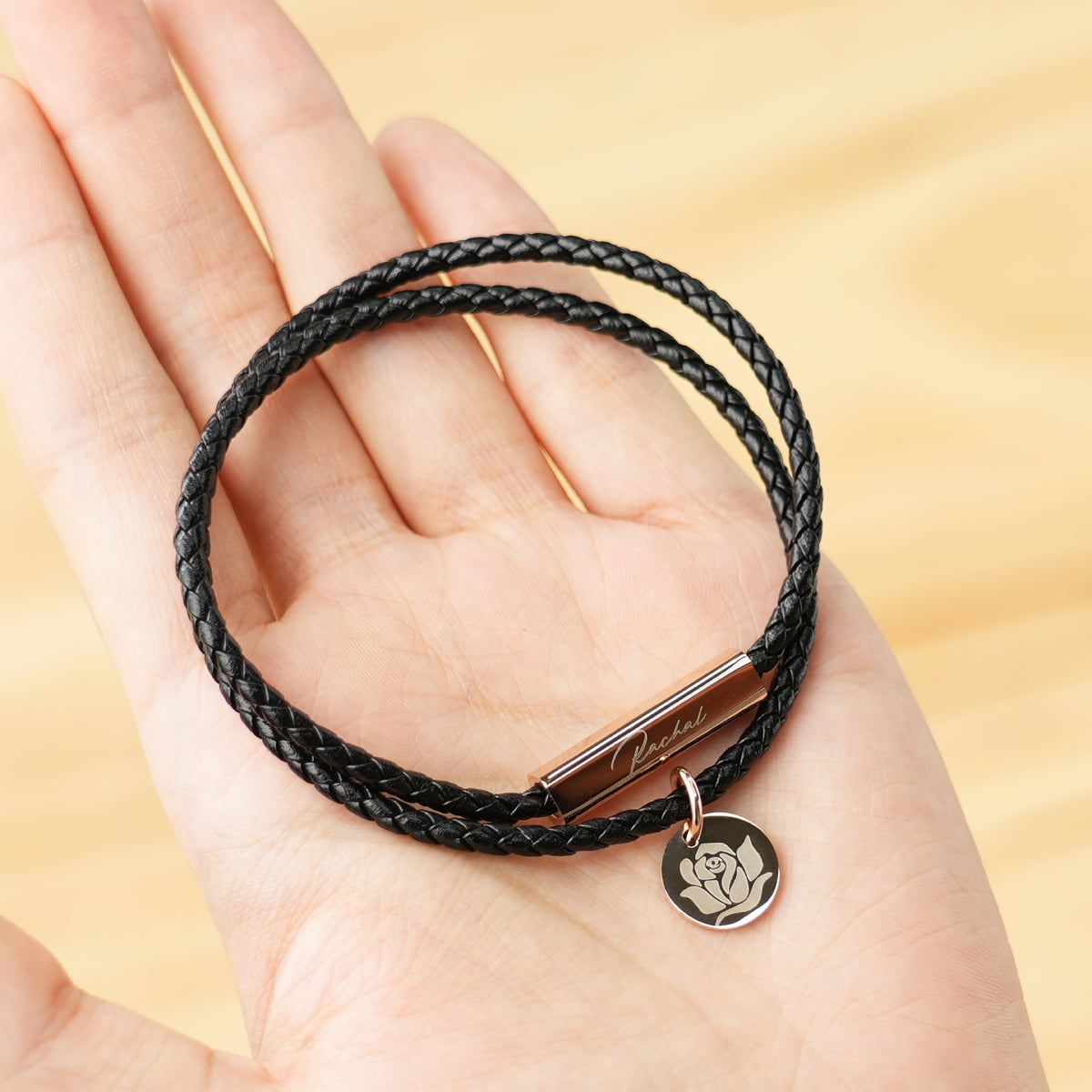 A woman holds the braided leather bracelet with custom engravings in the palm.