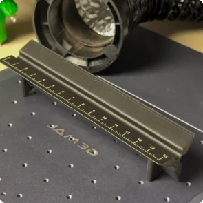 Un creador usa una LaserPecker LP4 para grabar con láser graduaciones de escala precisas en una regla triangular impresa en 3D.