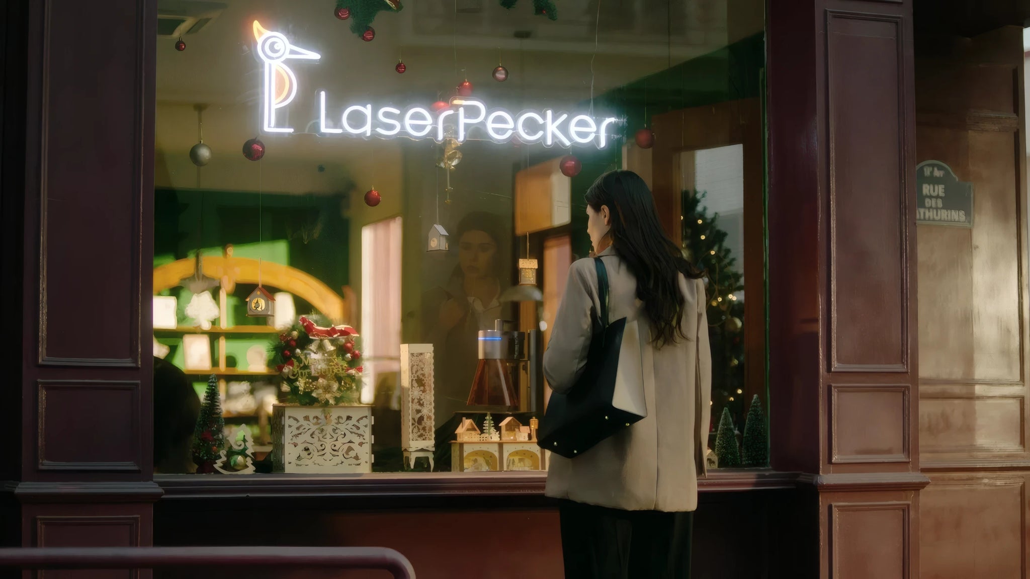 A woman standing outside a LaserPecker storefront window, captivated by the personalized engraved products displayed inside.