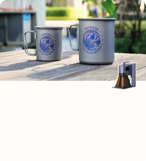 Two engraved camping mugs with outdoor-themed designs placed on a wooden table.