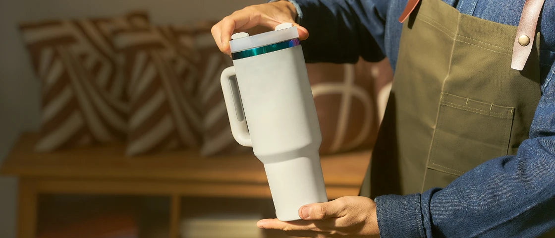 A white tumbler being held by hand.