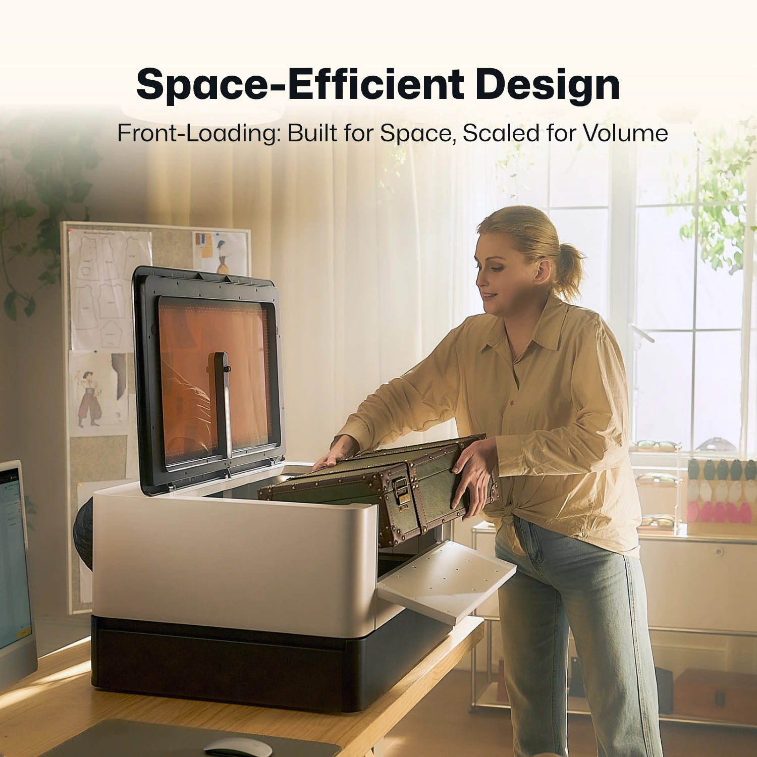 LaserPecker enclosed laser engraver demonstrating its space-efficient, front-loading design. A user loads a workpiece into the machine on a compact workspace, highlighting how the front-access design optimizes tabletop space while maintaining high-volume production capability.