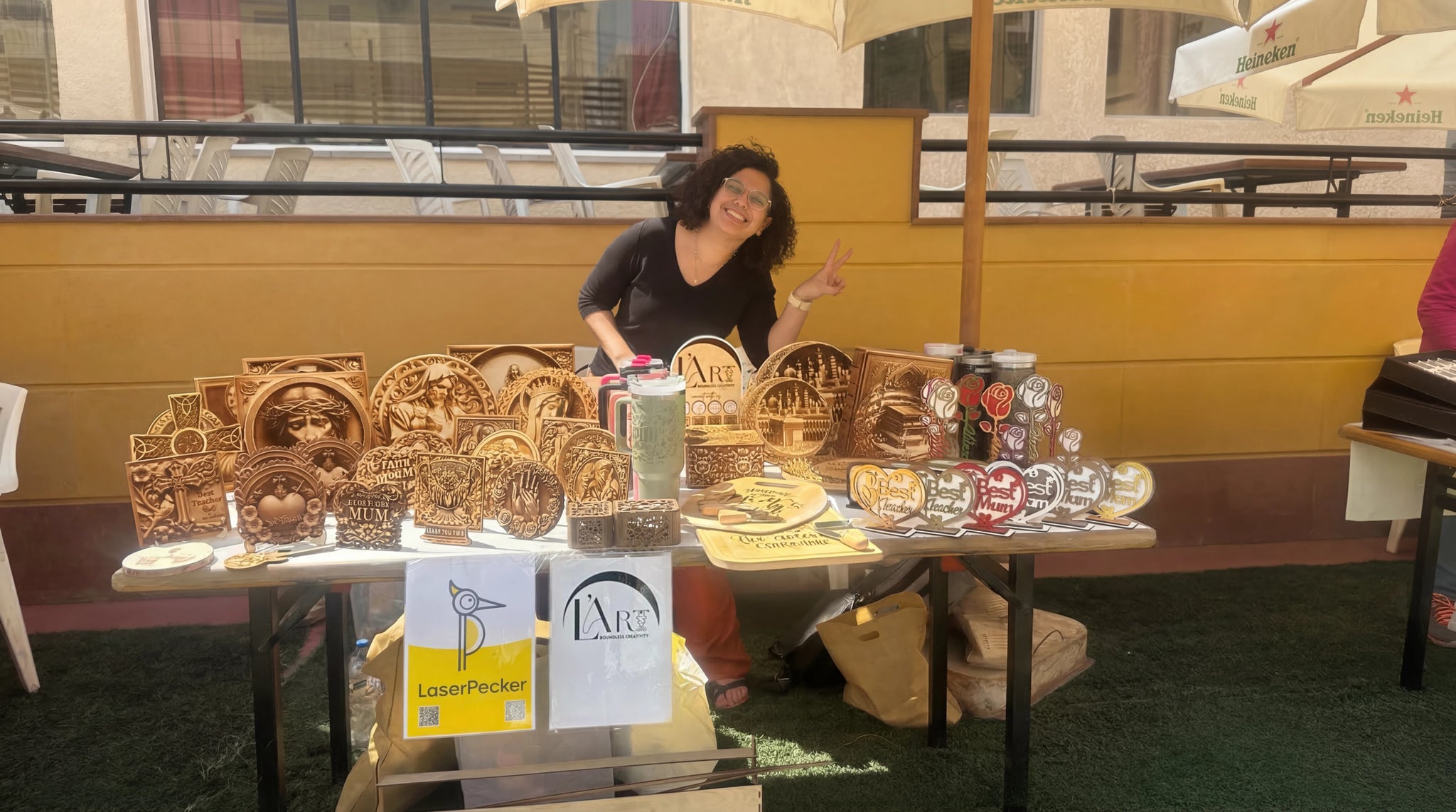 Des ornements en bois personnalisés sont en cours de gravure et exposés sur un stand de marché.