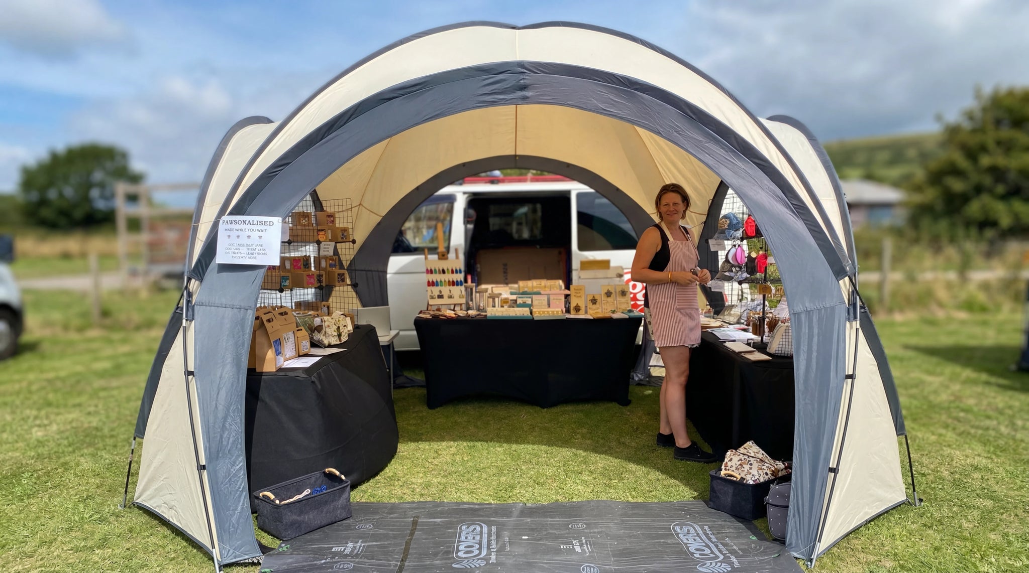 Un stand exposant des articles faits main et gravés, avec la vendeuse à côté de la présentation.