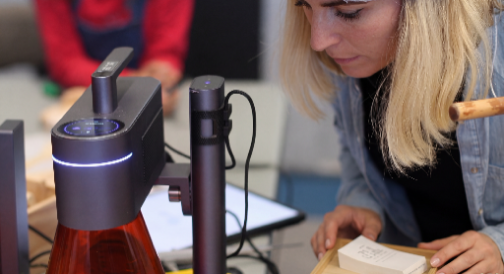 Une femme testant une machine LaserPecker pour graver un produit.