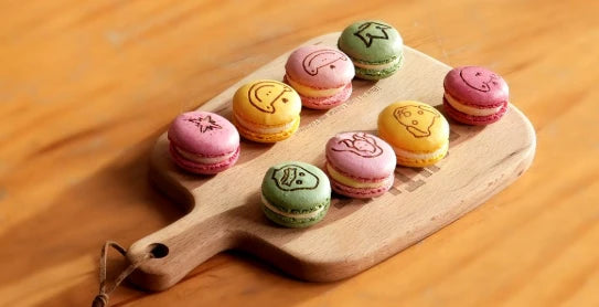 LaserPecker LP2 Plus precision laser engraving on colorful macarons, featuring various cute emoji and animal icons with clean, food-safe detailing.
