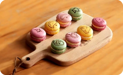 LaserPecker LP2 Plus precision laser engraving on colorful macarons, featuring various cute emoji and animal icons with clean, food-safe detailing.