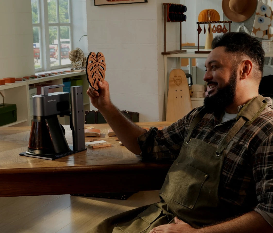 Craftsman presenting a laser-cut wooden leaf made with LaserPecker LP2 Plus portable laser engraver in a DIY workshop setting.