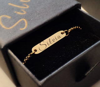 Un collier délicatement confectionné, gravé au nom d’une femme à l’aide d’une machine de gravure laser, présenté dans un écrin à bijoux.