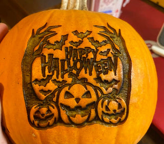 Une citrouille gravée avec les mots « Happy Halloween » et des éléments décoratifs effrayants.