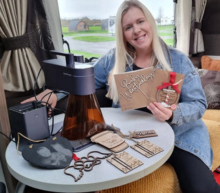 Une petite entrepreneuse assise à une table avec une machine de gravure laser LP4 et les produits créatifs qu’elle a réalisés.