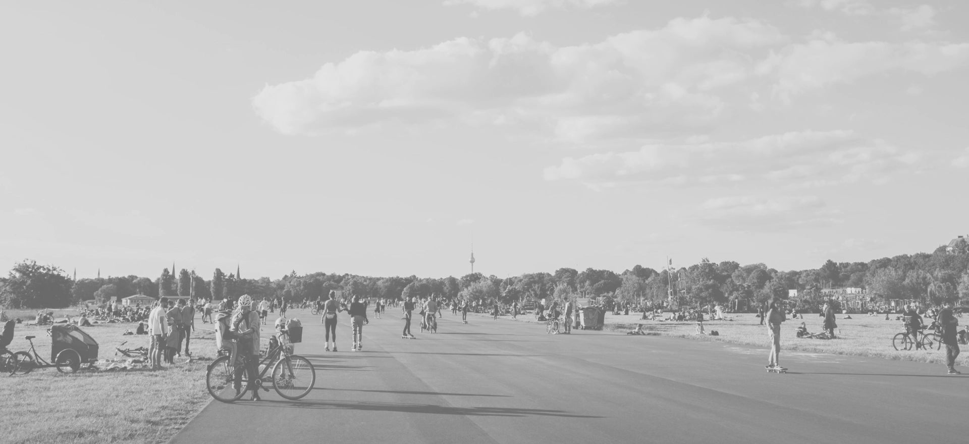 Une large route en Allemagne bordée de pelouses plates des deux côtés, où de nombreuses personnes se détendent et profitent du plein air.