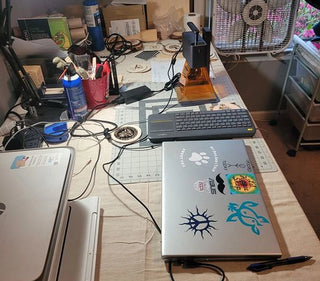 Un coin d’atelier avec une machine de gravure laser LP2 posée sur un bureau, à côté d’un ordinateur portable et d’un clavier utilisés pour la contrôler.