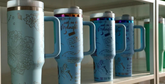 High-resolution laser etching on powder-coated metal tumblers, demonstrating the LaserPecker LP2 Plus's ability to produce fine-lined botanical patterns and script text for premium personalized merchandise.