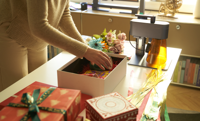 Une femme emballant divers produits gravés dans une boîte cadeau.