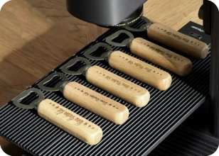 LaserPecker LP2 Plus using the Slide Extension to batch engrave custom logos on wooden handle bottle openers for promotional gifts.